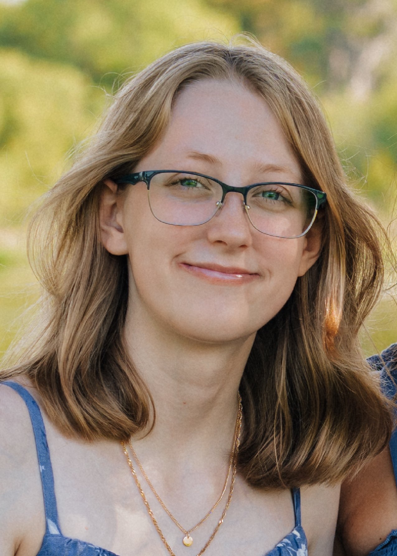 image of a young blonde woman smiling with glasses wearing a dress